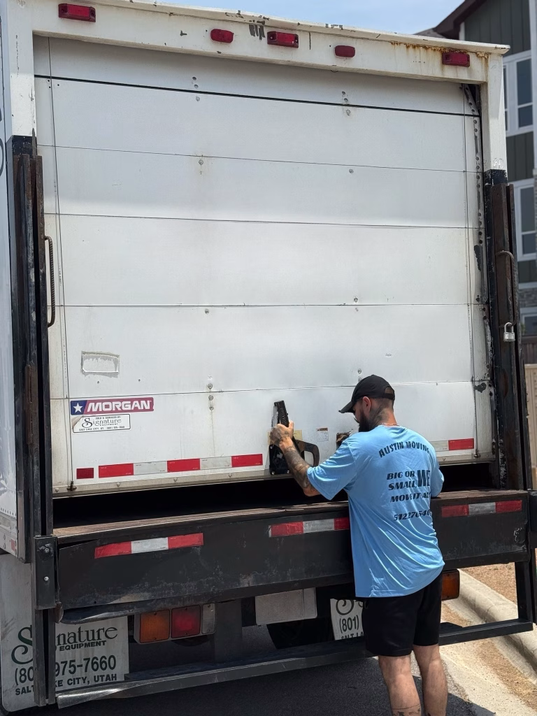 An Austin Moving Company professional unlatching and opening the back door of a large moving truck.